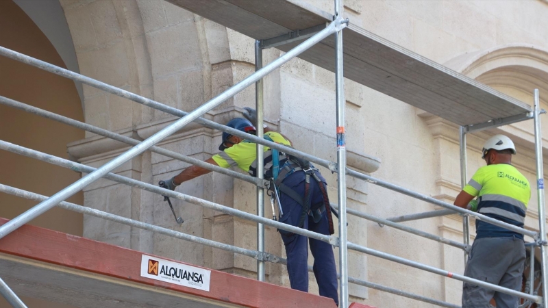 Dos operarios trabajando en el montaje de unos andamios en Sevilla.