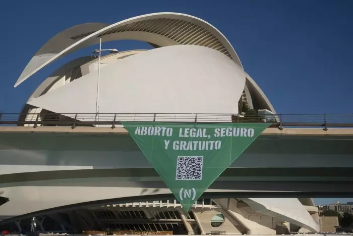 Un grupo de activistas descuelga un gran pañuelo verde en València en defensa del derecho al aborto