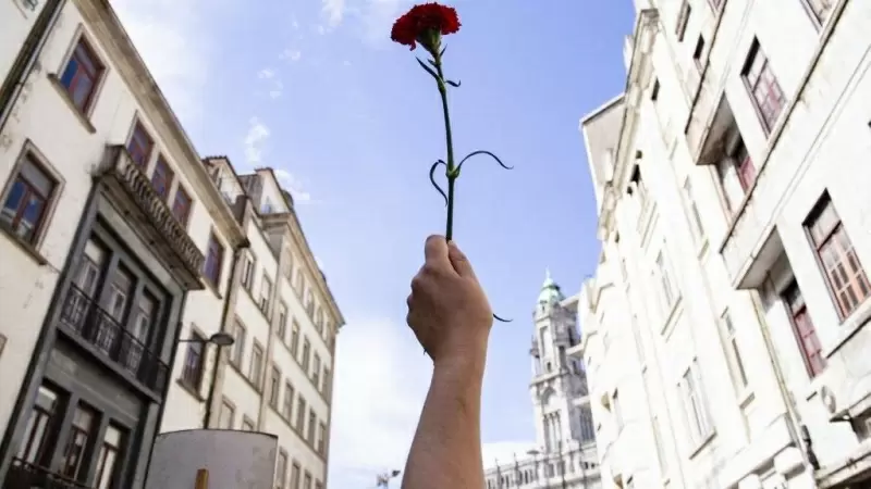 Una mujer sostiene un clavel rojo durante una manifestación para conmemorar el aniversario de la Revolución de los Claveles, a 25 de abril de 2021, en Oporto.