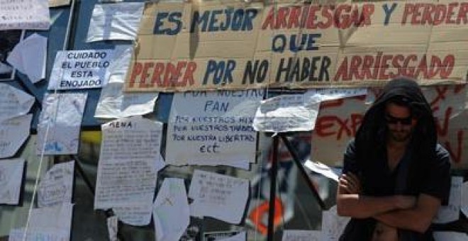 Uno de los participantes en la movilización junto a varios carteles situado en la Puerta del Sol de Madrid. fernando sánchez
