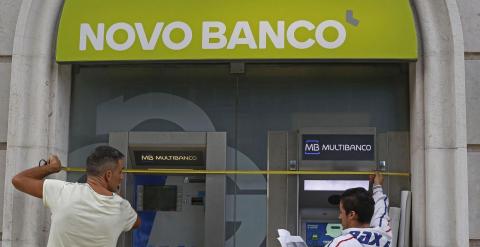 Dos operarios cambian el rótulo de una oficina del BES por su nuevo nombre Novo Banco. REUTERS