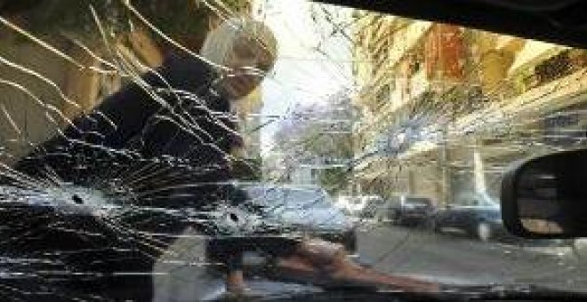 La vida no se para con la guerra. Una mujer limpia en Beirut el parabrisas de su coche que presenta varios impactos de bala. bela szandelsky / ap