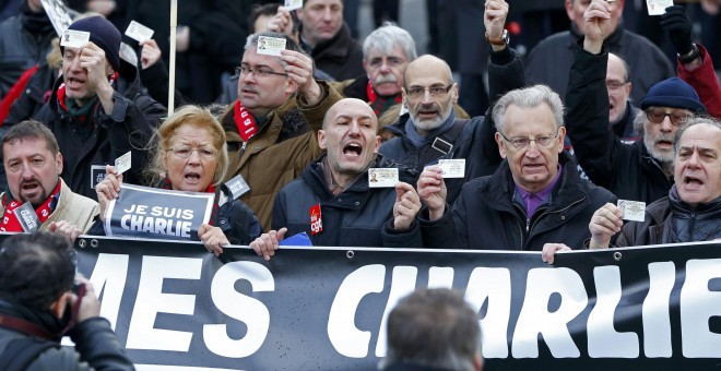 French journalists holding up their Press card take part in a hundreds of thousands of French citizens solidarity march (Marche Republicaine) in the streets of Paris January 11, 2015. French citizens will be joined by dozens of foreign leaders, among them
