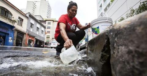 Una mujer se surte de agua debido a que su negocio sufre cortes de suministro. - EFE