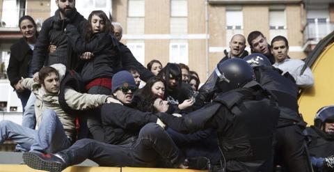 Antidisturbios tratan de retirar a varias personas de la excavadora usada durante el desalojo. EFE/Javier Lizón