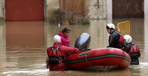 Voluntarios de Cruz Roja acompañan a una mujer hasta su casa por las calles anegadas del casco histórico de Tudela (Navarra), dentro de la atención que prestan a los vecinos que han quedado incomunicados por la crecida del río Ebro, desbordado a causa de