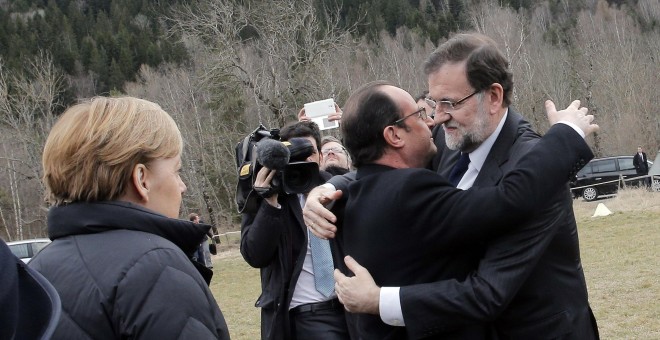 Mariano Rajoy y François Hollande se abrazan ante la mirada de Angela Merkel. REUTERS