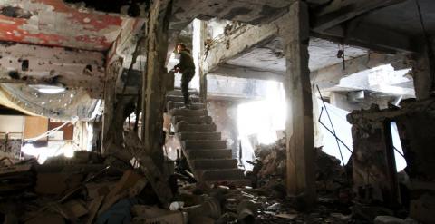 Un combatiente toma posición en las escaleras de un edificio destrozado por los bombardeos en Yarmuk. - YOUSSEF KARWASHAN / AFP
