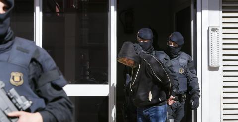 Agentes de los Mossos d'Esquadra custodian a una de las nueve personas que han sido detenidas en el marco de una operación contra el terrorismo yihadista que están llevando a cabo la policía catalana, coordinada por el juzgado número 1 de la Audiencia Nac