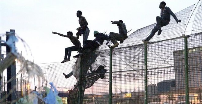 Un grupo de personas intentan saltar la frontera de Melilla. EFE