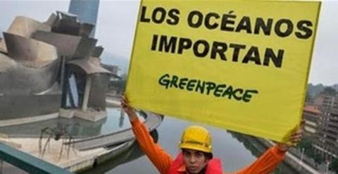 Un activista de Greenpeace, con una pancarta frente al Guggenheim de Bilbao. PEDRO ARMESTRE