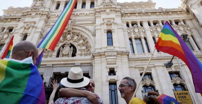 Una bandera con los colores del arco iris, símbolo LGTB, ondea en el Ayuntamiento de Madrid mientras algunas parejas homosexuales lo celebran en los aledaños del consistorio. REUTERS