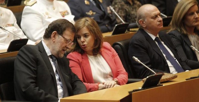 El presidente del Gobierno, Mariano Rajoy (i), conversa con la vicepresidenta, Soraya Sáenz de Santamaría, junto al ministro del Interior, Jorge Fernández Díaz (d), durante el acto que ha tenido lugar hoy en la Cámara Baja para rendir homenaje a las vícti