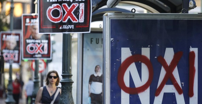 Pancartas en Atenas con el 'No' y otro en una parada de un autobús con una pintada. /REUTERS