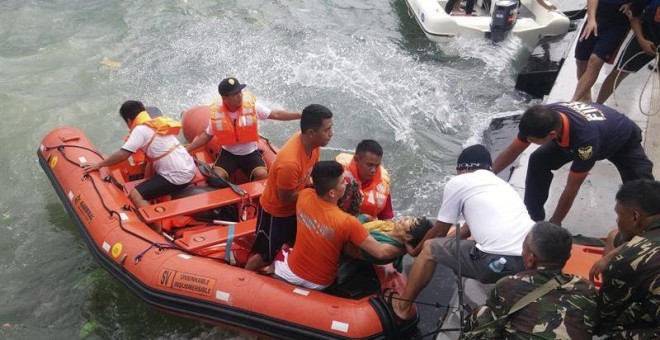 Miembros de un equipo de rescate recuperando los restos mortales de algunas de las víctimas de un naufragio frente al puerto de Ormoc