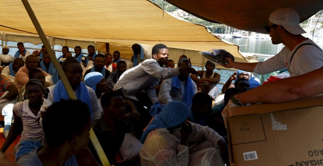 Un trabajador de Médicos sin Fronteras distribuye chanclas entre los inmigrantes rescatados. REUTERS