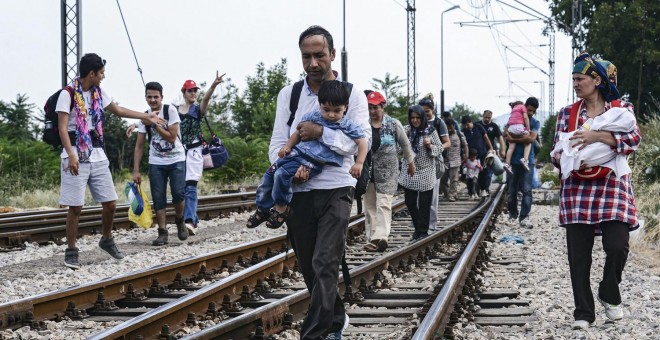 Inmigrantes caminan sobre las vías antes de tomar un tren con destino a  la frontera serbia en la localidad de Gevgelija, Macedonia EFE/Georgi Licovski