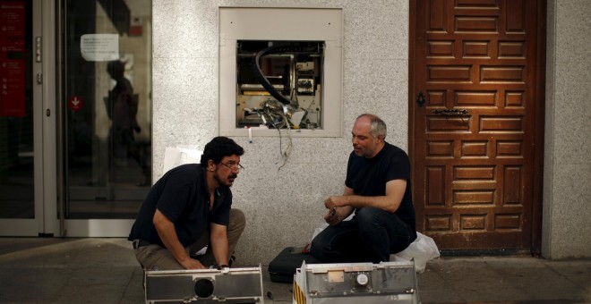 Fos operarios reparan un cajero automático en un banco en Ronda (Málaga). REUTERS/Jon Nazca
