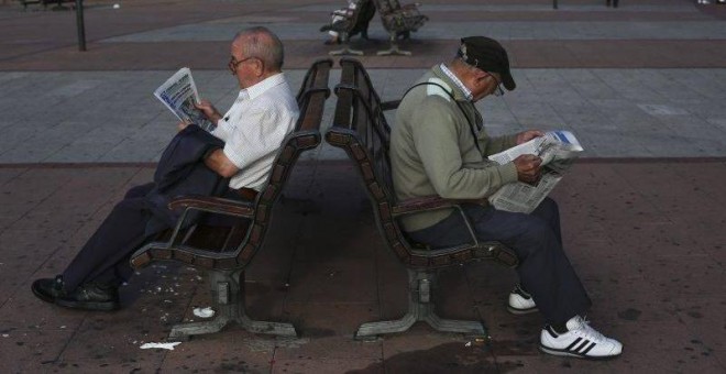 Dos pensionistas leen el periódico en un banco en Madrid. REUTERS