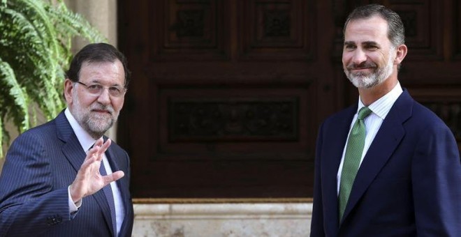 El rey Felipe VI saluda junto al presidente del Gobierno, Mariano Rajoy (i), hoy en el Palacio de Marivent, en Palma de Mallorca, donde se han reunido en el único despacho que ambos celebran este verano en la residencia de verano de la familia real. EFE/B