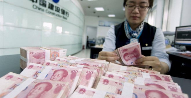 Una cajera del banco chino CCB cuenta billetes de yuan. REUTERS/China Daily