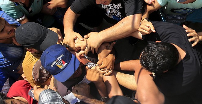 Refugiados sirios se amontonan para entrar en el estadio de la isla griega de Kos. REUTERS / Yannis Behrakis