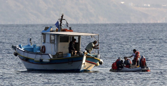 Un pescador griego auxilia a una familia siria que trata de llegar a la isla griega de Kros. REUTERS/Yannis Behrakis