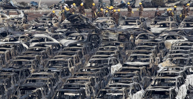 Los equipos de rescate se colocan cerca de los vehículos dañados cerca del lugar de las explosiones de la semana pasada en el nuevo distrito de Binhai en Tianjin, China. REUTERS