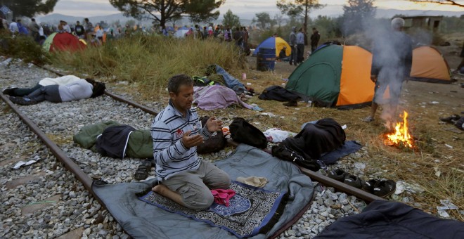 Un refugiado sirio reza sobre la vía férrea en la frontera entre Grecia y Macedonia, cerca del pueblo de Idomeni.- REUTERS