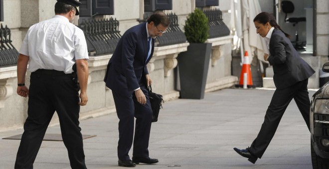 El presidente del Gobierno, Mariano Rajoy, se dispone a coger el móvil del suelo a su llegada al Congreso de los Diputados. EFE/Paco Campos