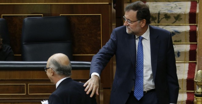 El presidente del Gobierno, Mariano Rajoy, felicita al ministro de Hacienda, Cristóbal Montoro, tras la intervención de éste ante el pleno del Congreso para defender los Presupuestos Generales del Estado para 2016. EFE/Paco Campos