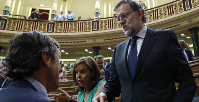 El presidente del Gobierno, Mariano Rajoy, conversa con el portavoz parlamentario del PP, Rafael Hernando, en presencia de la vicepresidenta, Soraya Sáenz de Santamaría, tras finalizar la votación en la que se rechazaron todas las enmiendas a los Presupue