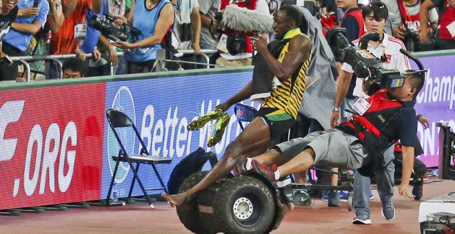 Bolt es arrollado por un cámara durante su celebración.-REUTERS