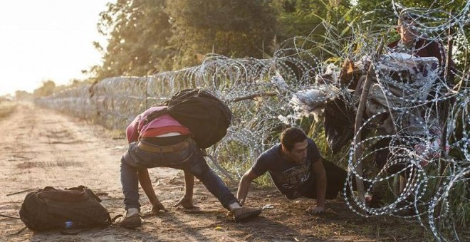 Varios refugiado pasan la alambrada en la frontera entre Hungría y Serbia cerca de Roszke (Hungría). / SANDOR UJVARI (EFE)