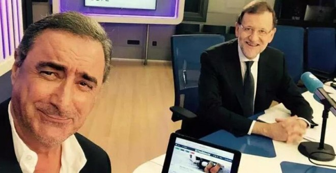 El presidente del Gobierno, Mariano Rajoy junto al periodista Carlos Herrera durante su entrevista en la cadena Cope. Foto del Twitter de Herrera. En la pantalla del ordenador se puede ver la foto del niño ahogado en la playa de Turquía.