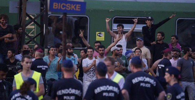 Centenares de refugiados esperan junto al tren regional que permanece varado en la estación de Bicske tras ser detenido ayer cuando se dirigía a Sopron, en la frontera con Austria. - EFE