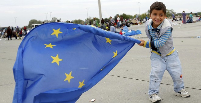 Un niño agita la bandera europea tras lograr cruzar la frontera entre Hungría y Austria. /REUTERS