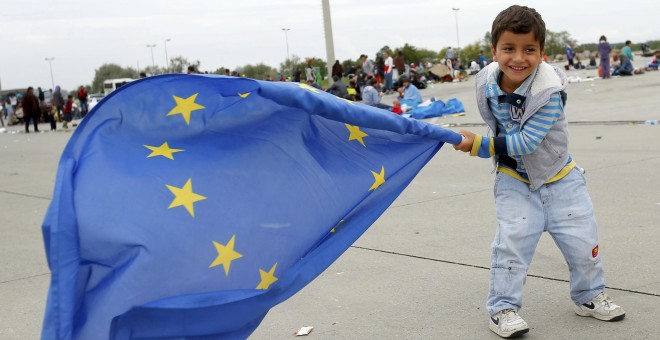 Un niño inmigrante juega con una bandera de la Unión Europea después de cruzar la frontera con Austria en Nickelsdorf, 5 de septiembre de 2015. REUTERS / Laszlo Balogh