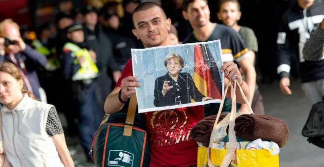 Un refugiado con una imagen de la canciller alemana, Ángela Merkel.- SVEN HOPPE (EFE)