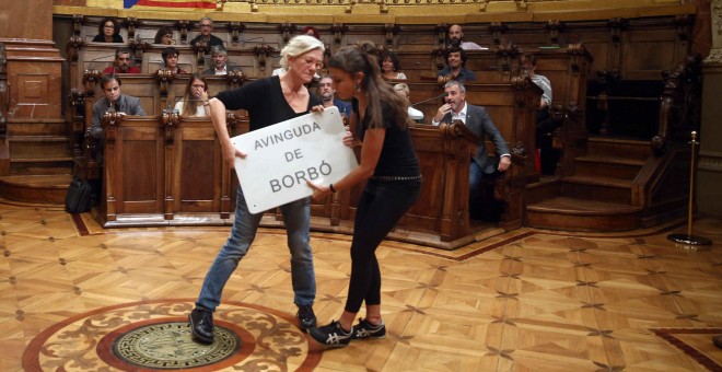 Las concejales de la CUP, Maria José Lecha y Maria Rovira, con una placa de la Avinguda de Borbó (Avenida de Borbón), como protesta a la presencia de referencias a la monarquía en las calles de Barcelona, durante el pleno  para debatir y votar si la capit