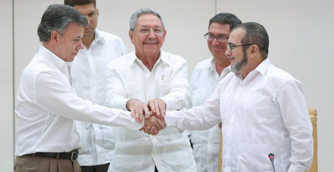 El presidente de Colombia, Juan Manuel Santos, se da la mano con el jefe de las FARC, Rodrigo Londoño 'Timochenko', en presencia del presidente de Cuba, Raúl Castro. - REUTERS