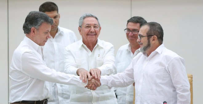 El presidente de Colombia, Juan Manuel Santos, se da la mano con el jefe de las FARC, Rodrigo Londoño 'Timochenko', en presencia del presidente de Cuba, Raúl Castro. - REUTERS