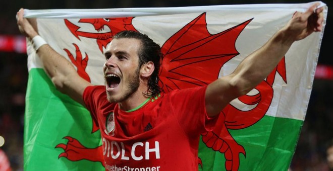 Gareth Bale porta una bandera de Gales en la fiesta de celebración de su clasificación para la Eurocopa 2016. /REUTERS