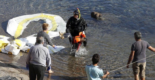 Un guardacostas griego saca del agua el cadáver de un niño refugiado en la costa griega de Lesbos. REUTERS/GIORGOS MOUTAFIS