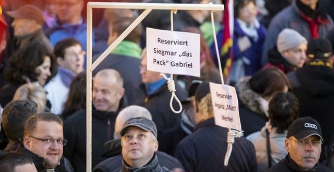 Simpatizantes de PEGIDA muestran una horca con mensajes amenazantes hacia Merkel. / REUTERS