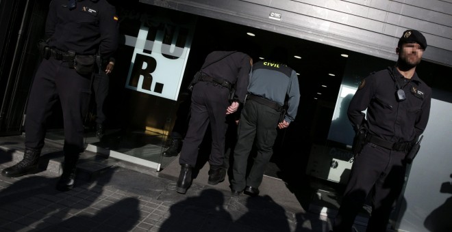 Agentes ante la fachada de la sede de CDC en Barcelona que esta siendo registrada. EFE
