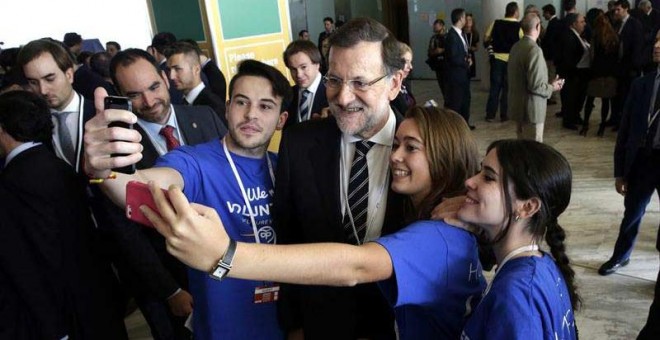 El presidente del Gobierno, Mariano Rajoy, se hace una foto con unos jóvenes a su llegadaa la segunda jornada del congreso que el Partido Popular Europeo celebra en Madrid. / ZIPI (EFE)