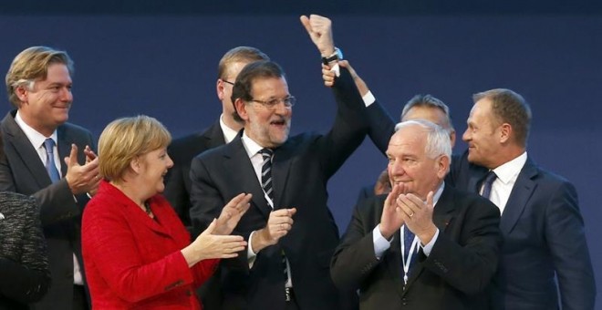 El presidente del Consejo Europeo, Donald Tusk (d), levanta el brazo del presidente del Gobierno, Mariano Rajoy (c), junto al presidente el PPE, Joseph Daul (2d), y la canciller alemana, Angela Merkel (2i), mientras posan para la foto de familia del Cong