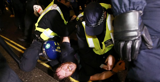 Un partidario del grupo activista Anonymous es detenido por agentes de policía durante una protesta en Londres. REUTERS