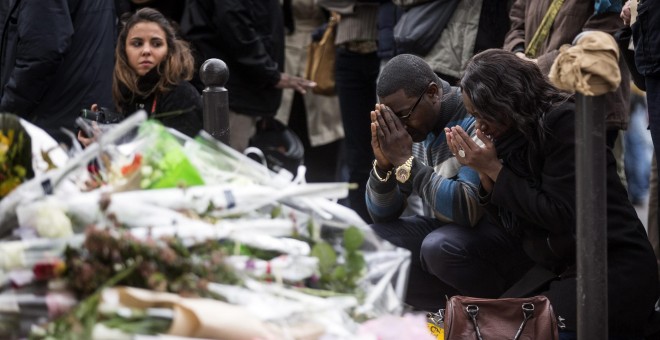 Numerosas personas guardan un minuto de silencio como homenaje a las víctimas de los atentados del viernes en la capital francesa ante el bar le Carillon de París. EFE